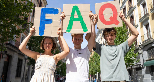 Häufige Fragen zum Spanisch-Sprachkurs in Madrid mit LISA! Sprachreisen Teilnehmer mit FAQ-Schildern während eines Spanisch-Sprachkurses für Young Adults in Madrid