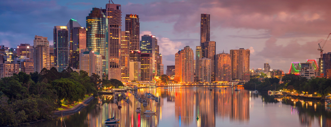 Beleuchtete Skyline von Brisbane spiegelt sich im Fluss bei Dämmerung während einer Sprachreise