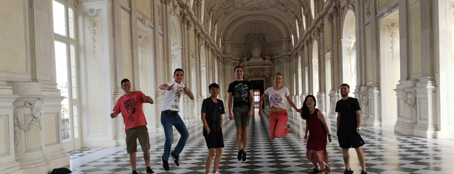 Mehrere Menschen springen freudig in einem barocken Saal bei einer LISA! Sprachreise in Turin