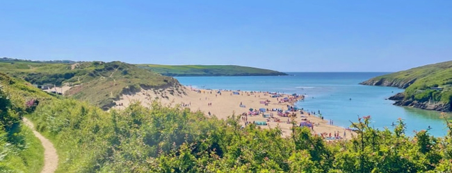 Blick vom Crantock Coast Path in Corwall auf eine Bucht am Meer mit Badenden