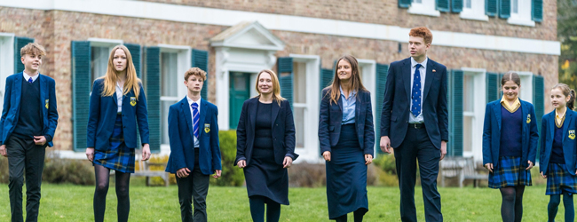 Schüler in Schuluniform stehen vor ihrer High School in England