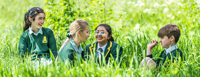 Vier Schüler sitzen im Gras mit Uniformen einer High School in England