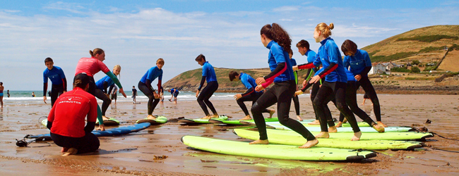 Surfkurs bei einer LISA! Sprachreise für Schüler in Ilfracombe Mehrere Kinder stehen am Strand auf Surfboards und lauschen den Surflehrern in Ilfracombe