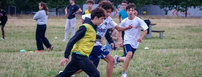 Jungen rennen hinter einem Ball her beim Fußball spielen in der Freizeit des Englisch-Sprachkurses