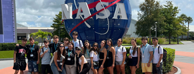 Jugendliche stehen vor dem NASA Symbol bei einem Ausflug