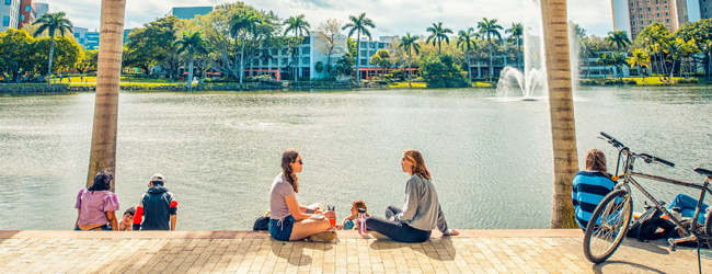 Zwei Mädchen sitzen am See vor der Universität in Miami mit Palmen