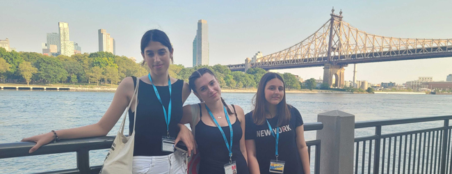 Drei Mädchen stehen am Hudson River vor einer Brücke und den Häusern von New York