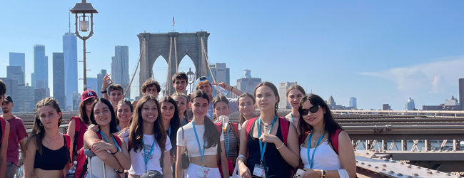 Schüler blicken froh in die Kamera auf der Brooklyn Bridge in New York