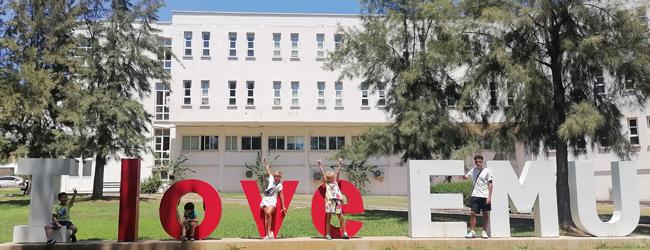 Kinder stehen zwischen großen Buchstaben vor der Universität in Famagusta